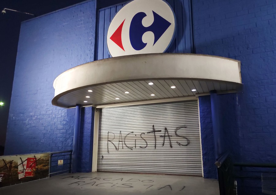 (FILES) This file photo taken on November 20, 2020 shows a graffiti written by demonstrators reading "Racists" at the entrance of a Carrefour supermarket in Curitiba, Brazil. - Brazilian police arrested on November 24, 2020, the supervisor of a Carrefour supermarket in Porto Alegre (south), as the alleged "co-author" of the brutal death of a black man who was beaten up by two store guards on November 19, 2020. (Photo by Guilherme BITTAR / AFP)