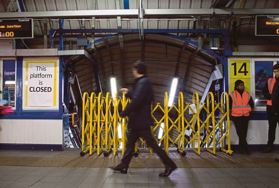 (FILES) In this file photo taken on January 10, 2017 a passenger walks past a closed entrance to a platform used by Southern Rail at Clapham Junction station in London on during a Southern Rail drivers strike. - (Photo by Daniel LEAL / AFP)