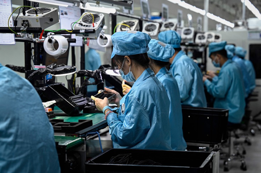 (FILES) This file photo taken on July 20, 2022 shows employees working on a smartphone assembly line at the Oppo factory in Dongguan, China's southern Guangdong province. - Factory output and retail sales in China edged up in July but were weaker than analysts' expectations, official data showed on August 15, 2022, as a Covid-19 resurgence and property market jitters cast a pall over hopes for a stronger economic recovery. (Photo by Jade GAO / AFP)