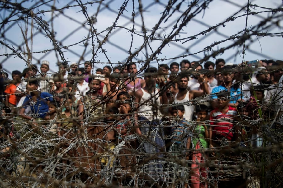 Rohingya refugees gathering behind a barbed-wire fence in a temporary settlement setup in a "no man's land" border zone between Myanmar and Bangladesh. -AFP file pic