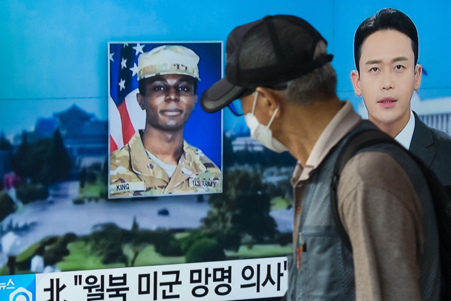 (FILES) A man walks past a television showing a news broadcast featuring a photo of US soldier Travis King (centre), who ran across the border into North Korea while part of a tour group visiting the Demilitarised Zone on South Korea's border. (Photo by Anthony WALLACE / AFP)