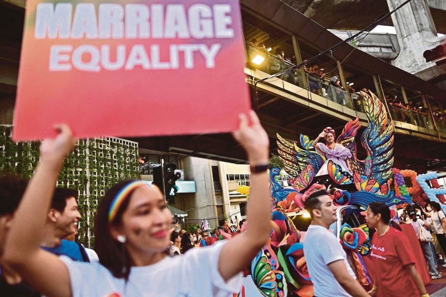 (FILES) A member of the LGBTQIA+ community holds a placard calling for marriage equality during a pride march in Bangkok. (Photo by MANAN VATSYAYANA / AFP)