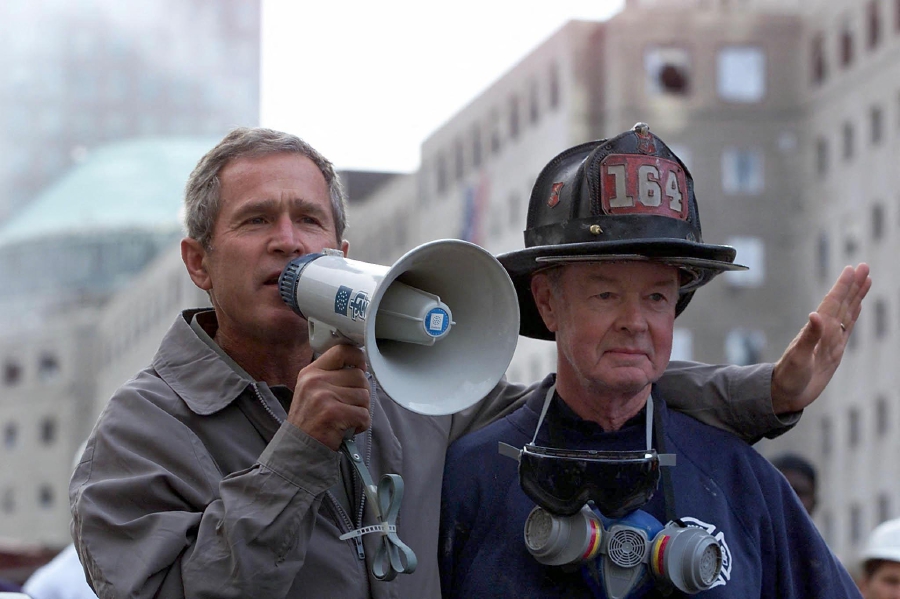 (FILES) US President George W. Bush (left), standing next to retired firefighter Bob Beckwith speaks to volunteers and firemen as he surveys the damage at the site of the World Trade Center in New York. (Photo by Paul J. RICHARDS / AFP)