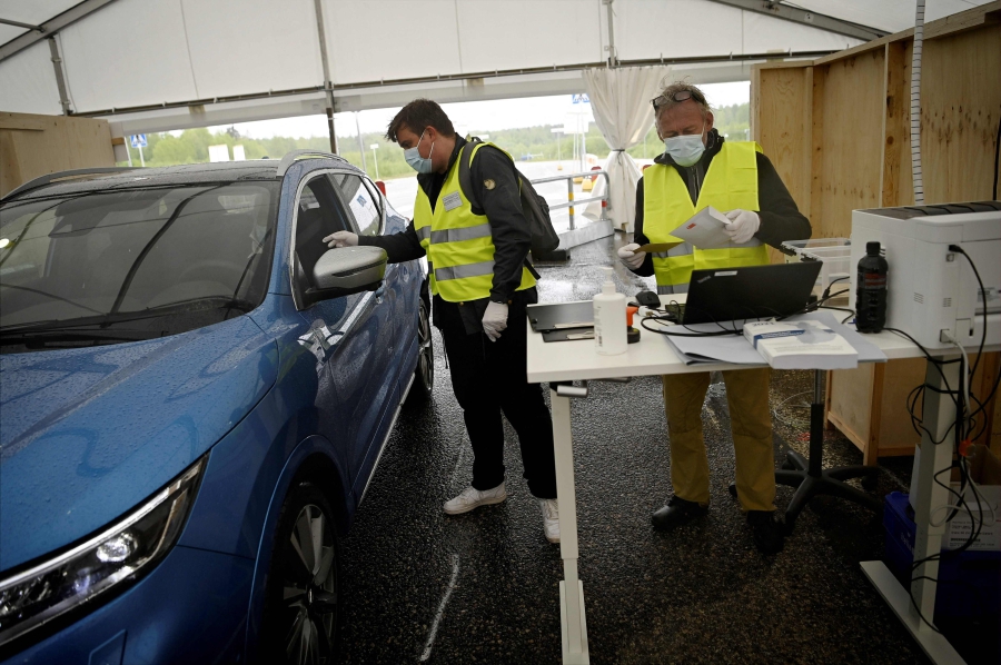 A car driver casts a ballot for municipal elections at a drive-in polling station at Malmi Airport in Helsinki, Finland, on May 26, 2021. - Outdoor polling stations have sprung up across the Nordic country as authorities try to make voting as socially distanced as possible ahead of the country's local elections on June 13, 2021. (Photo by Antti Aimo-Koivisto / Lehtikuva / AFP)  