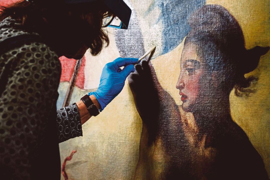 A restoration artist works on the restoration of the painting "Liberty Leading the People" (1830) by French artist Eugene Delacroix (1798-1863), at a laboratory inside the Louvre Museum in Paris. (Photo by Dimitar DILKOFF / AFP) 