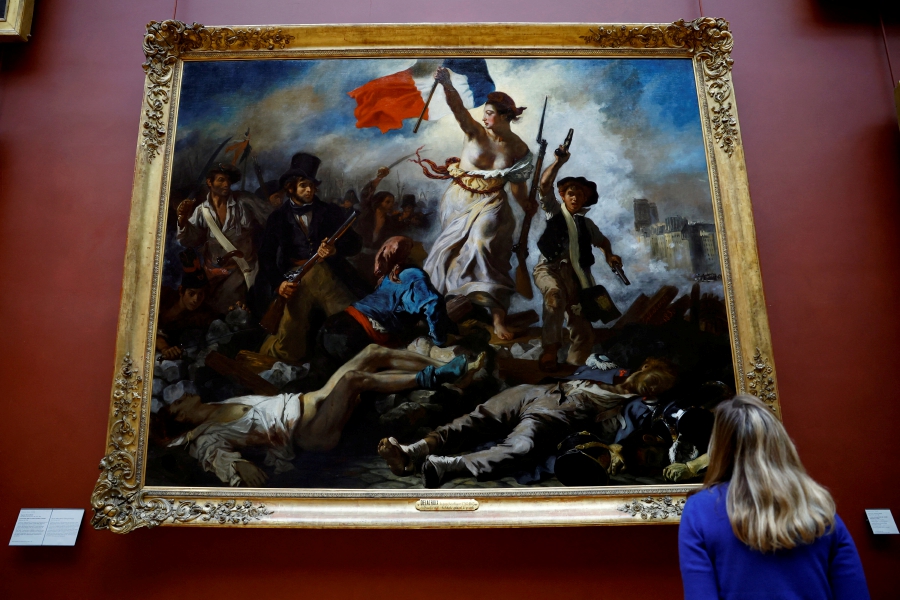 An employee looks at the painting "La Liberte guidant le peuple, 1830" (Liberty Leading the People) by Eugene Delacroix (1798-1863) after its reinstallation following six months of restoration work, at the Louvre museum in Paris, France. (REUTERS/Sarah Meyssonnier)