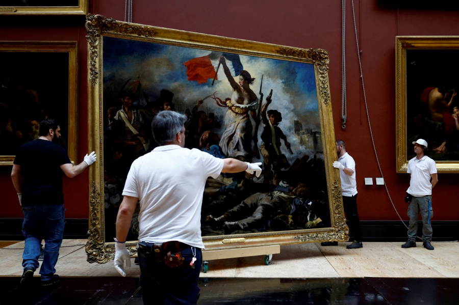 Employees install the painting "La Liberte guidant le peuple, 1830" (Liberty Leading the People) by Eugene Delacroix (1798-1863) after six months of restoration work, at the Louvre museum in Paris, France. (REUTERS/Sarah Meyssonnier)