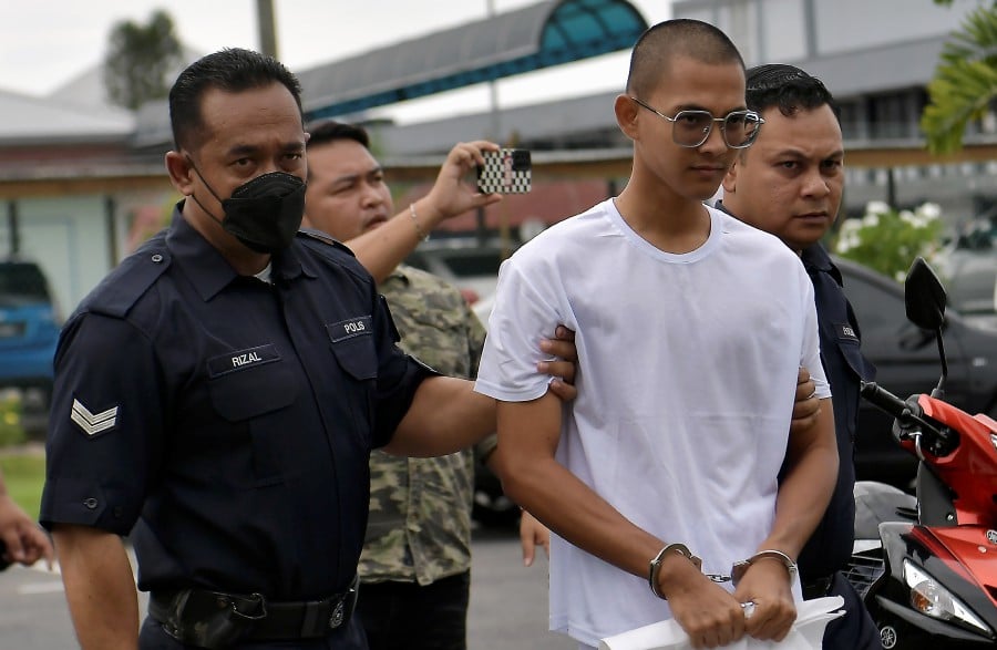 A file pic dated Sept 26, 2023, shows Muhammad Fakrul Aiman Sajali being escorted by policemen ahead of his trial at the Sungai Besar magistrate’s court. - BERNAMA PIC