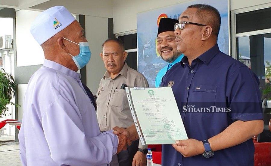 Menteri Besar Datuk Seri Muhammad Sanusi Md Nor presented the land titles to the settlers at the Langkawi District Office here. - NSTP/ HAMZAH OSMAN 