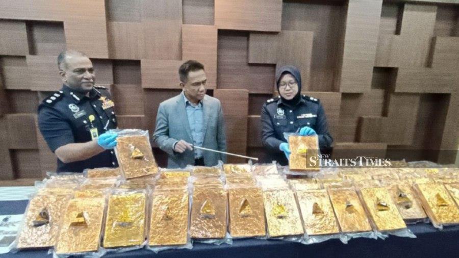Kedah police chief Datuk Fisol Salleh (centre) and two of his officers with the compressed cannabis seized from a homestay after police arrested a man suspected of being a trafficker. NSTP/ZULIATY ZULKIFFLI