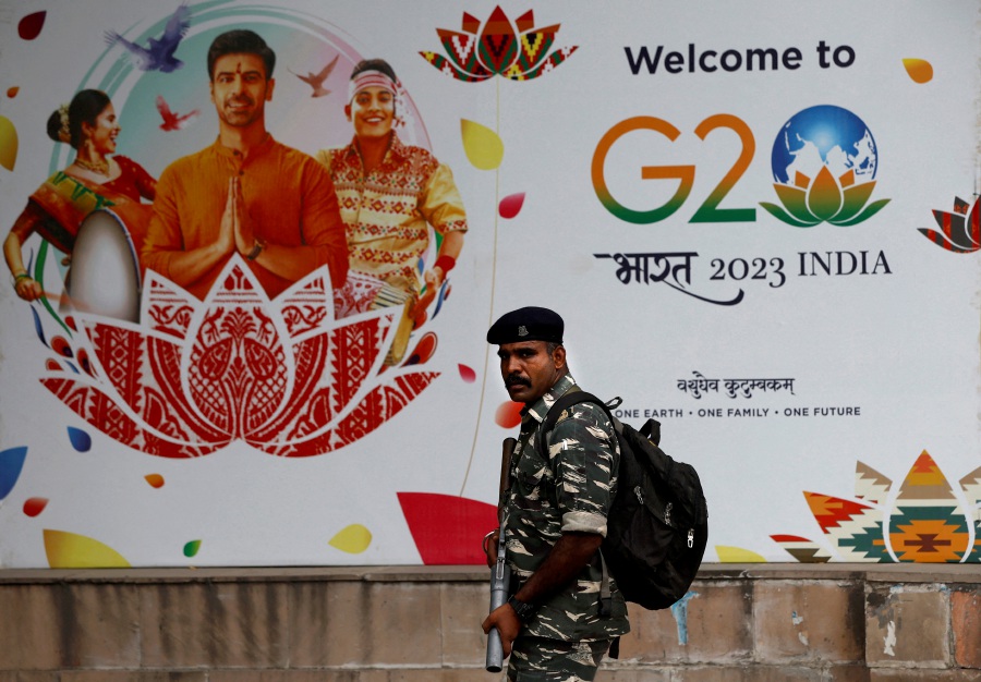 A Central Reserve Police Force personnel patrols a road next to a hoarding ahead of the G20 Summit in New Delhi, India. - Reuters pic