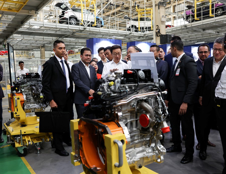 Han (centre) was taken on a tour of the factory floor while witnessing the various models produced by Proton. -- Bernama photo