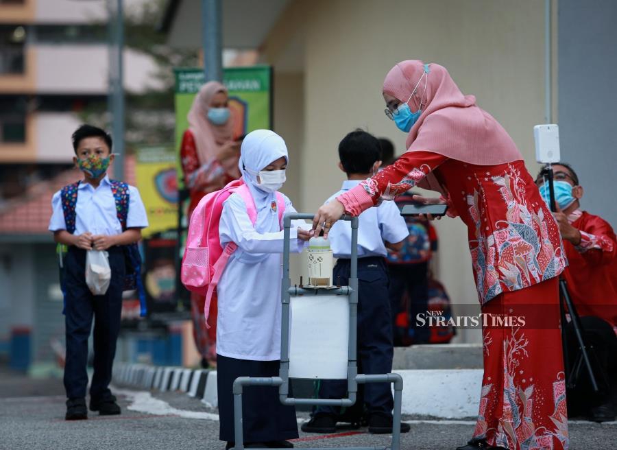 This file pic dated March 1, shows a teacher helping a student to use hand sanitiser before the start of the session at Sekolah Kebangsaan Seri Perak in Kuala Lumpur. -NSTP/ASWADI ALIAS.