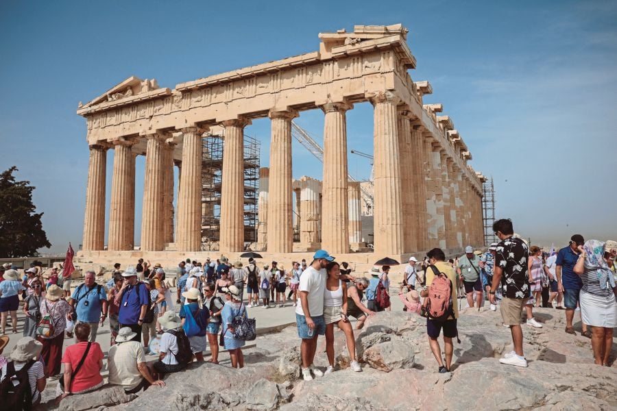 Tourists visit the Parthenon temple atop the Acropolis hill archaeological site before it closes due to a heatwave hitting Athens, Greece, on Thursday (June 13). — REUTERS