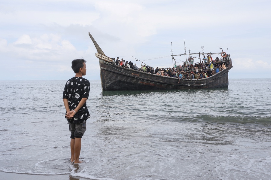 A local youth looks at a boat carrying newly arrived Rohingya refugees. (Pic for illustration purposes only) 
