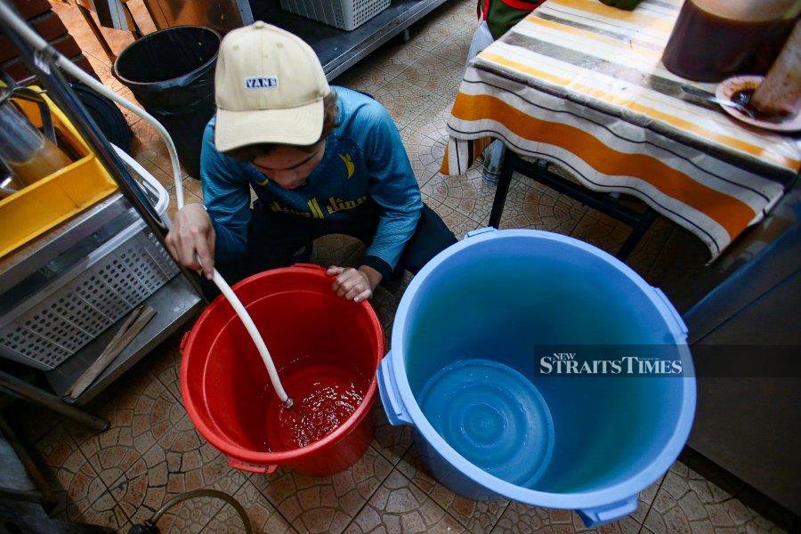 Nasi Ayam Mancongkam employee, Yusuf stores water in water barrels in preparation for scheduled water supply disruptions in several areas in the Petaling, Klang, Shah Alam, Gombak and Kuala Lumpur districts. - NSTP/GULITAH GENES