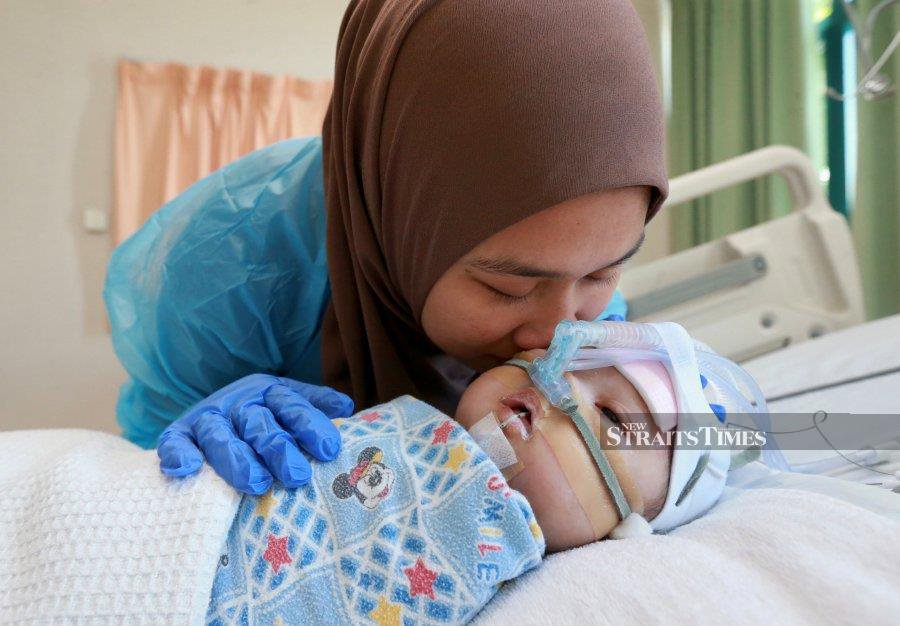 Abbil Haqim A. Aziz can only cry when looks at his baby son Muhammad Arifbillah Abbil Haqim. - NSTP/FATHIL ASRI.