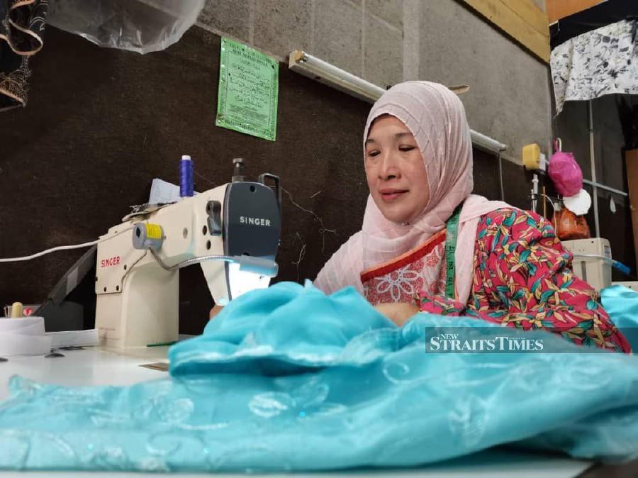 Hajrah sewing a baju raya for one of the customers in Kota Kinabalu. - NSTP/YUN MIKAIL