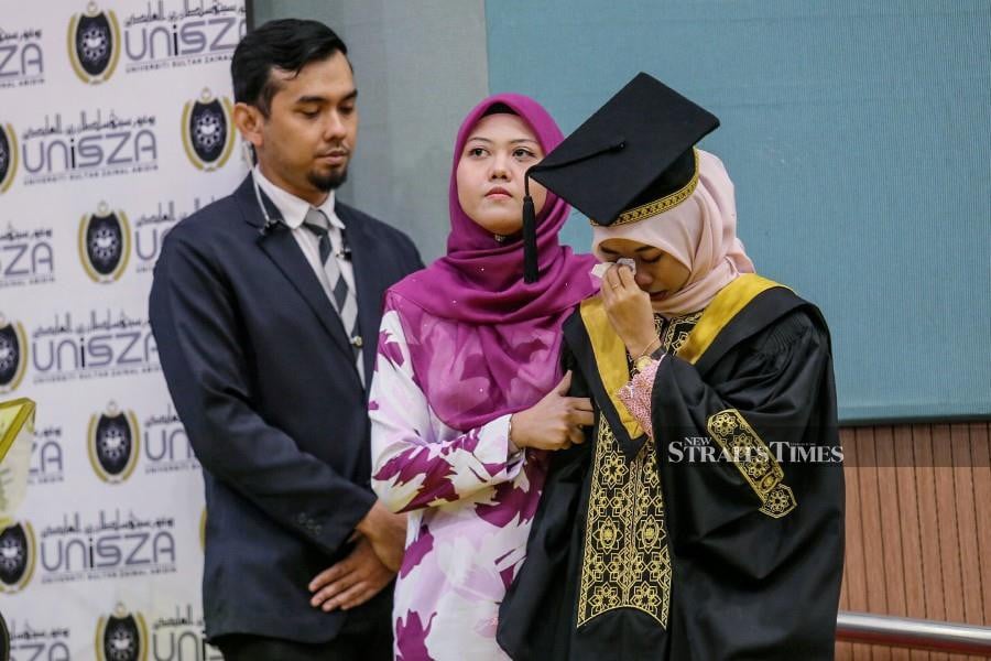 Haslina Kalang (right) is comforted by her friends during the convocation ceremony in Gong Badak. - NSTP/GHAZALI KORI