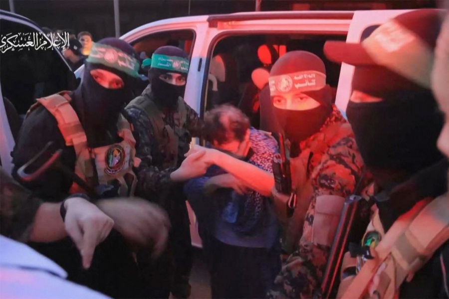 An image grab from a handout video released by the Hamas Media Office shows a member of its Al-Qassam Brigades helping a hostage out of a ar before handing them over to officials from the International Committee of the Red Cross in Gaza. - AFP pic