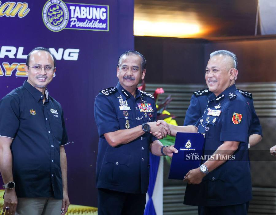 Inspector-General of Police (IGP) Tan Sri Razarudin Husain (centre) presenting an Excellent Service Awards (APC) to a senior police officer as a recognition of their excellent performance. - NSTP/ASWADI ALIAS.
