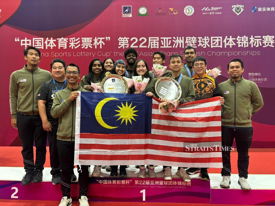  The Malaysian players pose with their trophies and medals after winning the men’s and women’s titles at the Asian Team Squash Championships in Dalian, China. on Sunday. PIC FROM SRAM