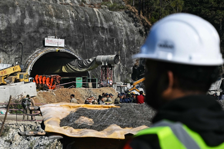 A rescue personnel stands near an entrance of the Silkyara under construction road tunnel, during the final phase of a rescue operation, days after a portion of it collapsed in the Uttarkashi district of India's Uttarakhand state. (Photo by Arun SANKAR / AFP)
