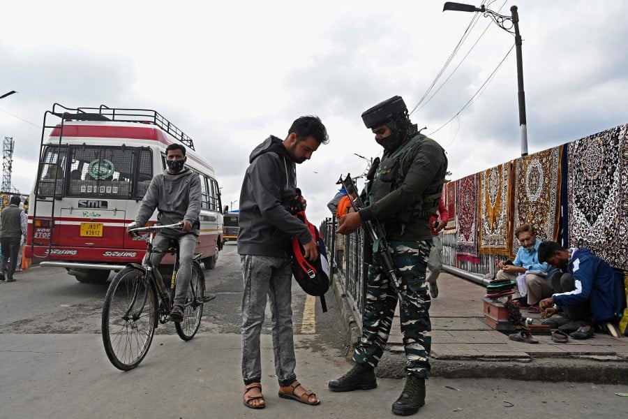 A security personnel checks the bag of a pedestrian along a street in Srinagar on October 11, 2021, as suspected militants shot dead five soldiers in Indian-administered Kashmir. AFP pic
