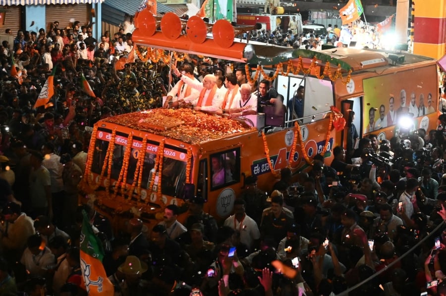 India's Home Minister and leader of the Bharatiya Janata Party (BJP) Amit Shah (centre) greet his supporters during a roadshow in Bengaluru, ahead of the second phase of voting of India's general election. (Photo by Idrees MOHAMMED / AFP)