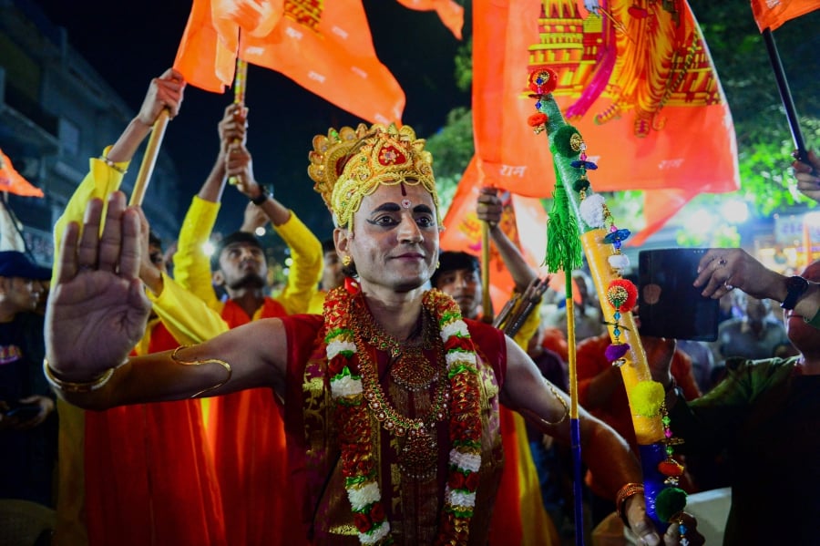 An artist dressed as Hindu deity lord Ram, arrives to perform on the eve consecration ceremony of Ram temple, during an event in Ahmedabad. (Photo by Sam PANTHAKY / AFP)