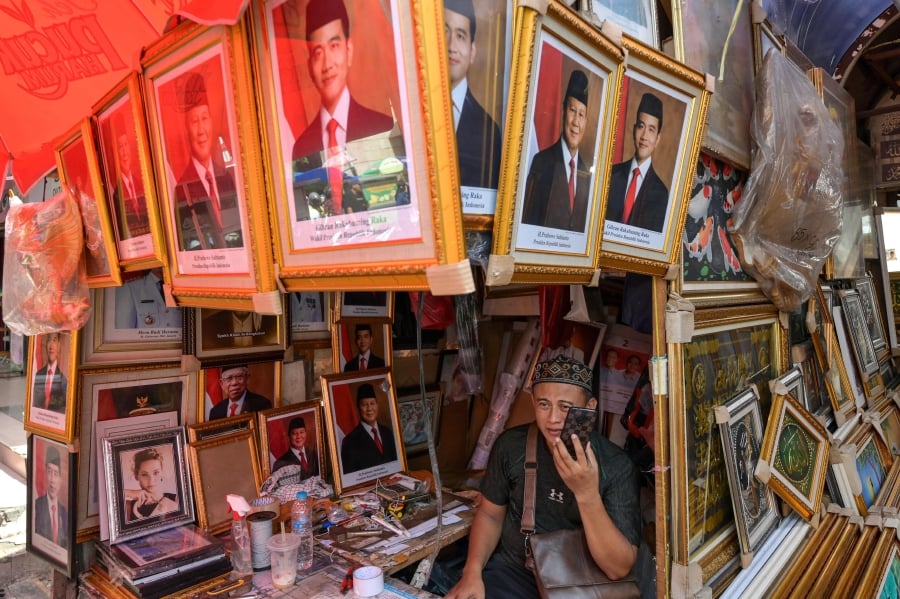 A vendor sells pictures of Indonesia's President-elect Prabowo Subianto (second from right) and Vice president-elect Gibran Rakabuming Raka (centre) at his kiosk in Jakarta. (Photo by BAY ISMOYO / AFP)