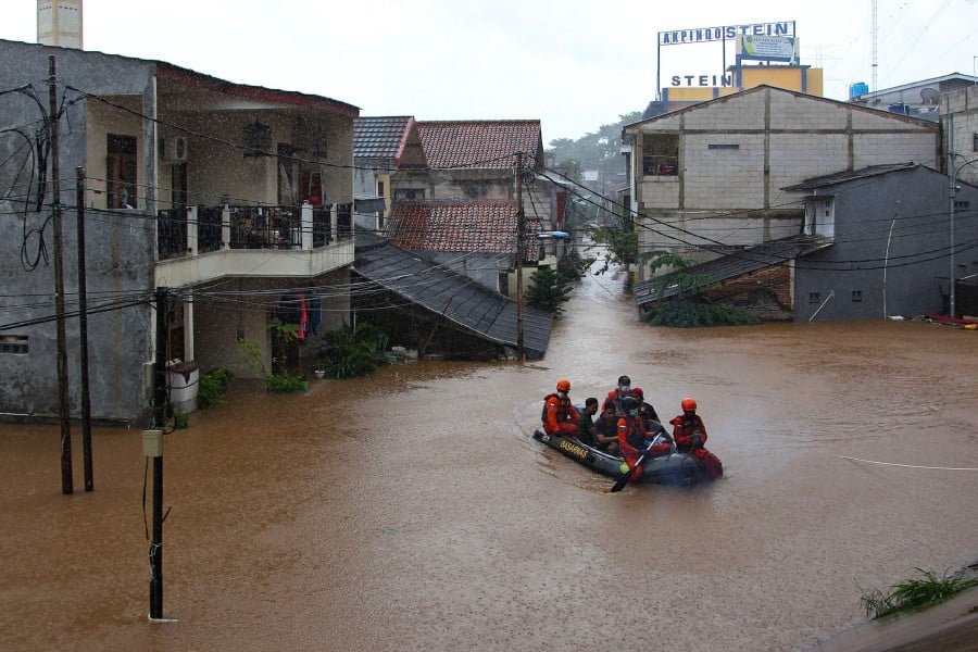  Rescue personnel paddle a raft through a flood-affected neighbourhood in Jakarta on February 20, 2021, following heavy overnight rains. (Photo by DASRIL ROSZANDI / AFP)