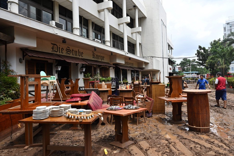 People put muddy furniture from a restaurant out to dry in Kemang in Jakarta on February 21, 2021, a day after parts of Indonesia's capital were inundated with flooding from seasonal heavy rains. (Photo by ADEK BERRY / AFP)