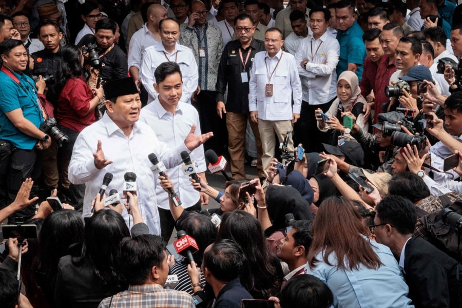 Indonesia's president-elect Prabowo Subianto (left) speaks to the media with vice president-elect Gibran Rakabuming Raka (2nd L) as they arrive at the plenary session of the General Elections Commission (KPU). (Photo by Yasuyoshi CHIBA / AFP)