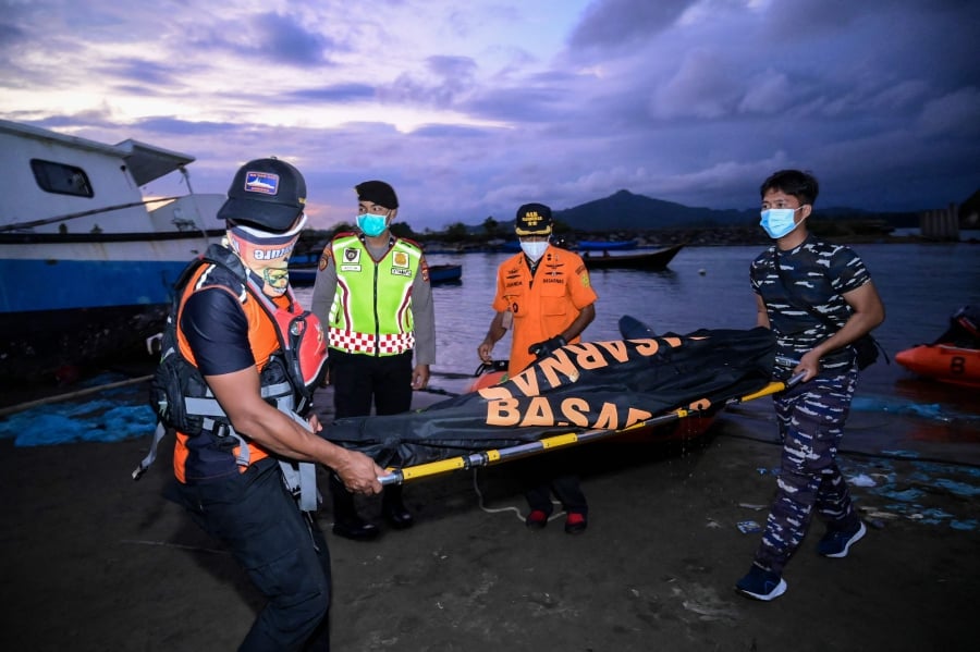 Members of the National Search and Rescue Agency (BASARNAS) carry a recovered body in a bodybag during the search operation for missing Rohingya refugees after 69 refugees were rescued from their overturned boat two days ago in the sea in Calang, West Aceh. (Photo by Zahlul AKBAR / AFP)