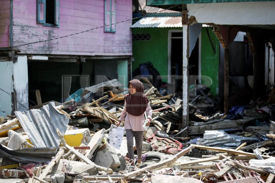 epa07065834 An Indonesian girl walks on the rubble of a collapsed house at a tsunami devastated area in Donggala, Central Sulawesi, Indonesia, 03 October 2018. According to reports, at least 1,407 people have died after a series of powerful earthquakes hit Central Sulawesi on 28 September 2018 and triggered a tsunami. EPA/MAST IRHAM