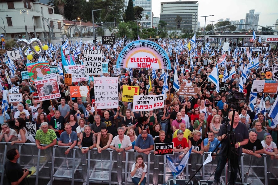 Left-wing activists lift placards and national flags during an anti-government demonstration in the Israeli coastal city of Tel Aviv. (Photo by JACK GUEZ / AFP)