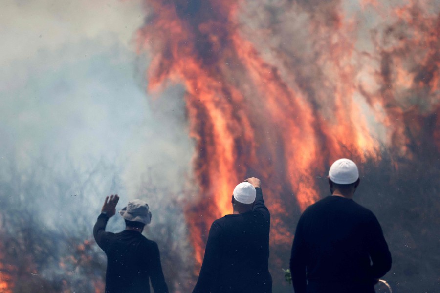 Local Druze men watch the flames burning a field after rockets launched from southern Lebanon landed on the Banias area in the Israel-annexed Golan Heights on Sunday (June 9), amid ongoing cross-border clashes between Israeli troops and Hezbollah fighters. — AFP