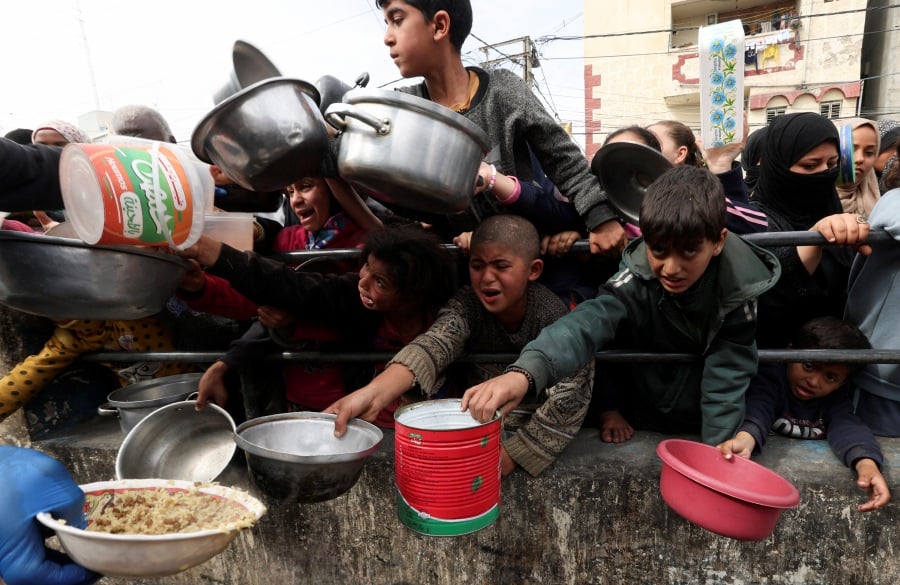 Palestinian children wait to receive food cooked by a charity kitchen amid shortages of food supplies in Rafah, in the southern Gaza Strip, February 13, 2024. - REUTERS pic