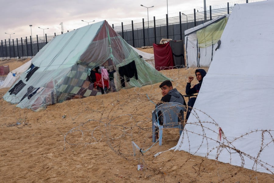 Displaced Palestinians, who fled their houses due to Israeli strikes, amid the ongoing conflict between Israel and the Palestinian Islamist group Hamas, sit outside a tent at the border with Egypt, amid fears of an Israeli ground assault in Rafah, in the southern Gaza Strip February 18, 2024. REUTERS PIC