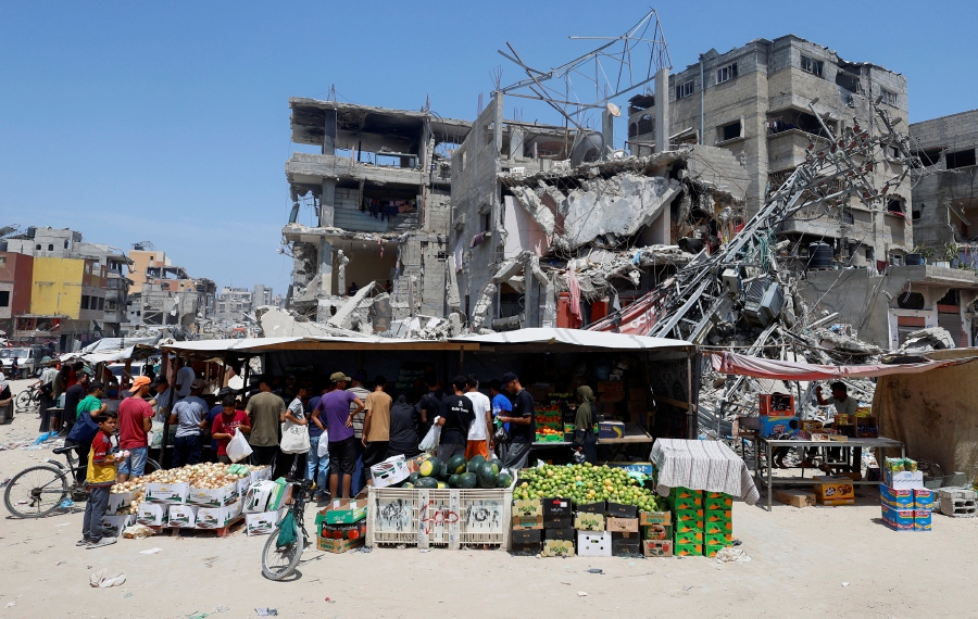 Palestinians shop at a makeshift market set up next to buildings destroyed in an Israeli strike. 9REUTERS/Mohammed Salem)