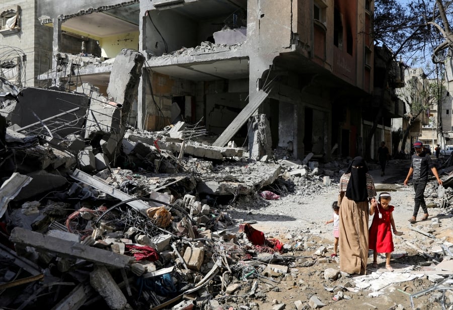 (FILE PHOTO) A woman and child walk among debris, aftermath of an Israeli strikes. (REUTERS/Abed Khaled/File Photo)