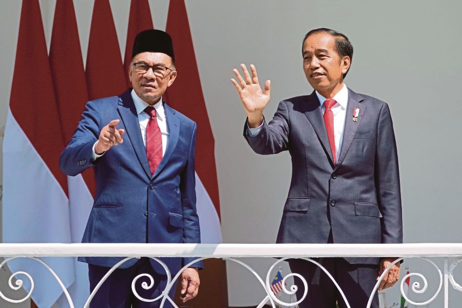 Indonesian President Joko Widodo, right, and Malaysia's Prime Minister Anwar Ibrahim wave at journalists during their meeting at the presidential palace in Bogor, West Java, Indonesia. (AP Photo/Achmad Ibrahim)