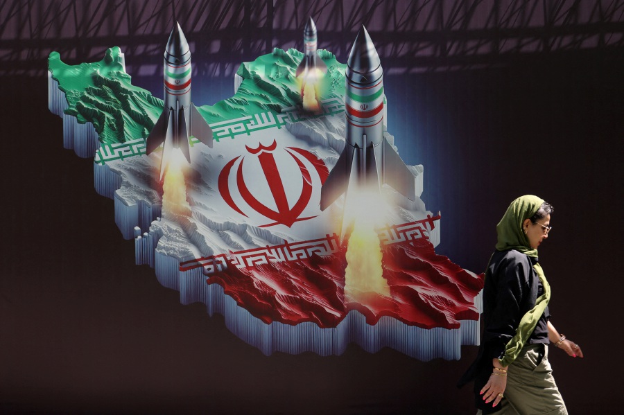 An Iranian woman walks past an anti-Israel banner with a picture of Iranian missiles on a street in Tehran, Iran. - Majid Asgaripour/WANA (West Asia News Agency) via REUTERS