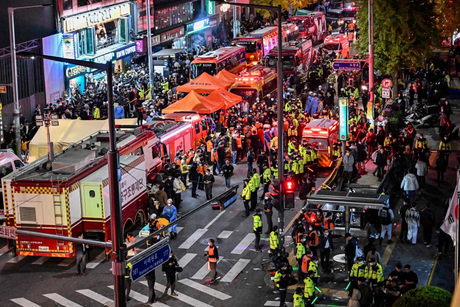 Onlookers, police and paramedics gather where dozens of people suffered cardiac arrest, in the popular nightlife district of Itaewon in Seoul. - AFP PIC