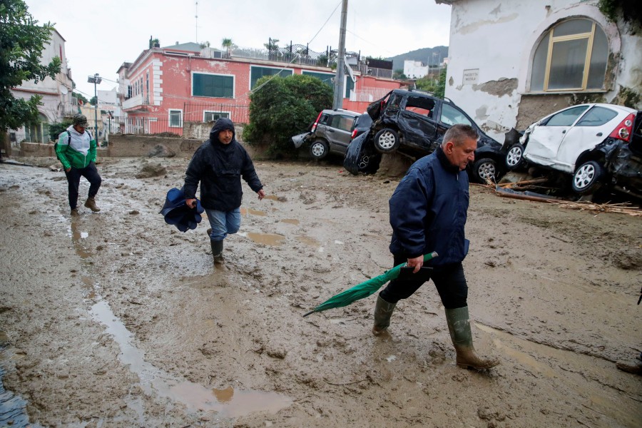 People walk through mud in a flooded road after heavy rainfall triggered landslides that collapsed buildings and left as many as 12 people missing, in Casamicciola, on the southern Italian island of Ischia, Saturday. Firefighters are working on rescue efforts as reinforcements are being sent from nearby Naples, but are encountering difficulties in reaching the island either by motorboat or helicopter due to the weather. - AP pic
