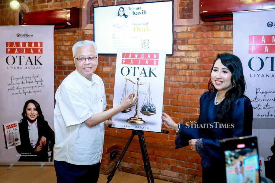 Former prime minister Datuk Seri Ismail Sabri Yaakob with Jangan Pajak Otak’s writer Liyana Marzuki (right) during the launch at Bungalow 37, Kuala Lumpur . NSTP/ASYRAF HAMZAH