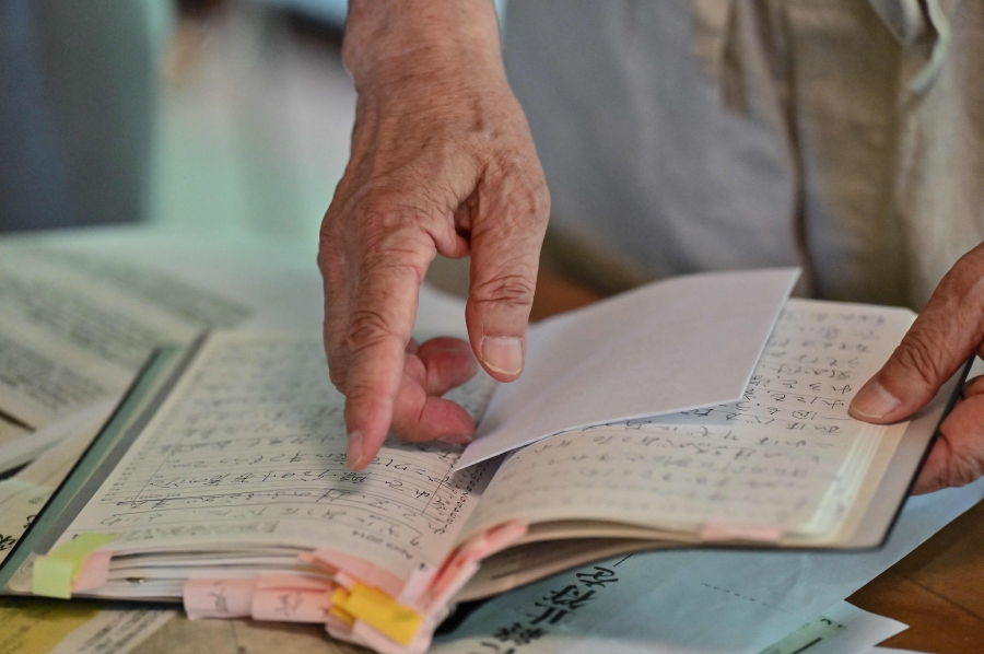 Chief Buddhist priest Eiichi Shinohara looking at a diary of a woman who was swindled out of millions of yen. (Photo by Richard A. Brooks / AFP) 