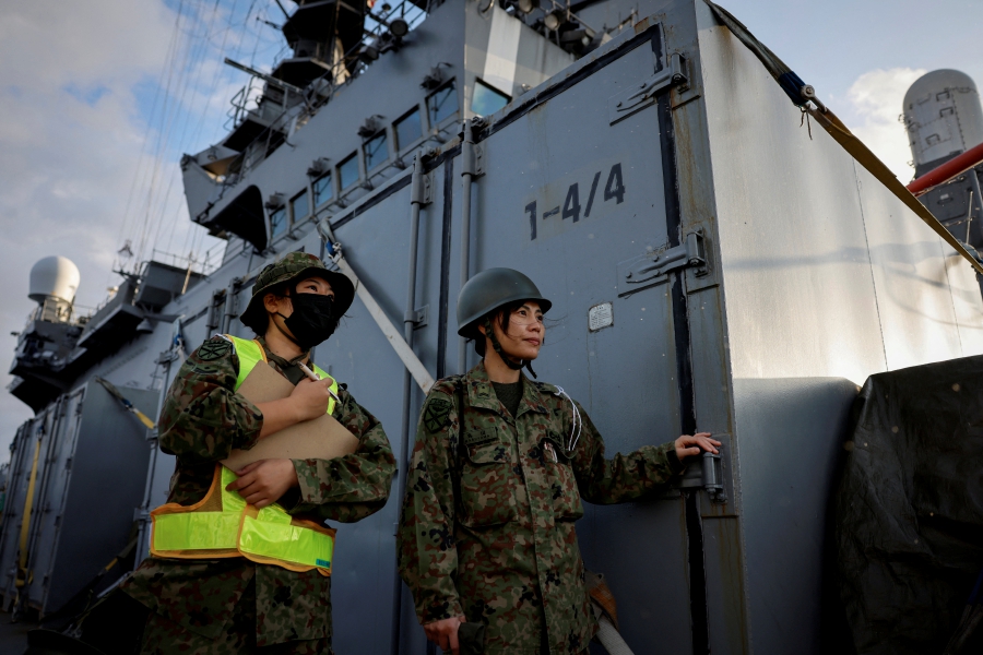 Hikari Maruyama and Runa Kurosawa, soldiers with the Japanese Ground Self-Defense Force's Amphibious Rapid Deployment Brigade (ARDB) watch a helicopter land on the flight deck on the Japanese Maritime Self-Defense Force's amphibious transport ship JS Osumi (LST-4001) in waters close to Okinawa, Japan. (REUTERS/Issei Kato)