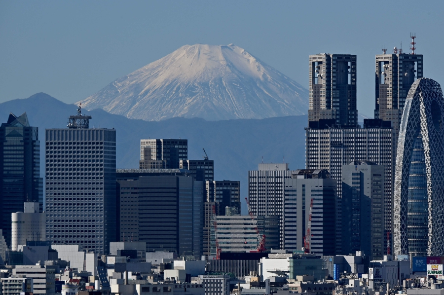 Japan's highest mountain, Mt. Fuji in the background between skyscrapers in Tokyo's Shinjuku area. (Photo by Kazuhiro NOGI / AFP)